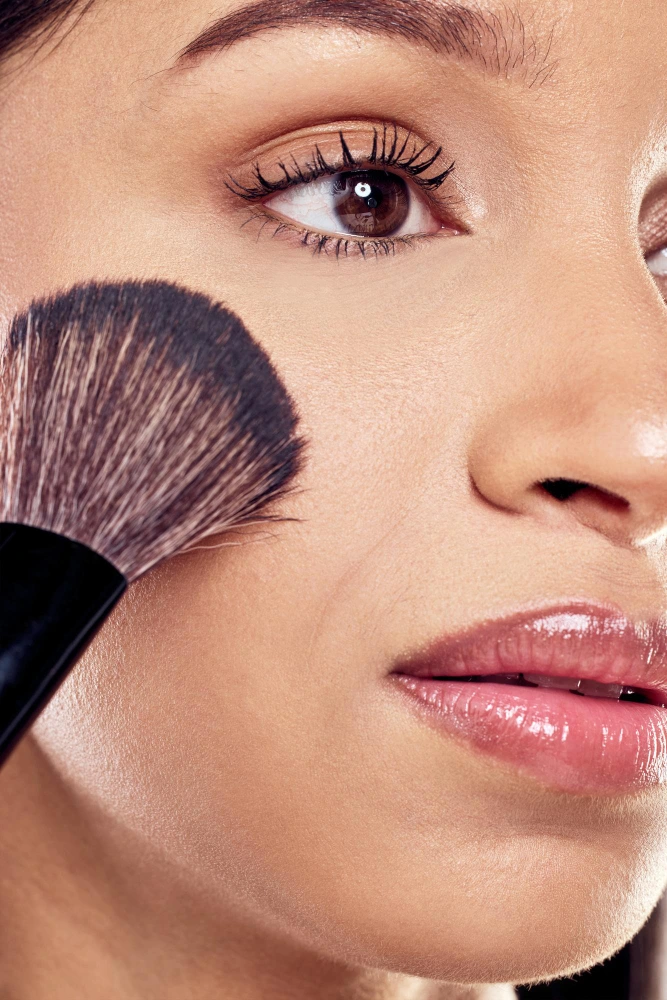 detalle de brocha maquillando rostro mujer